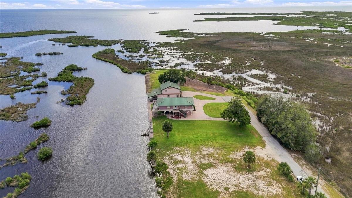 Sweeping aerial view across the property, coastal wetlands, and Gulf of America beyond.