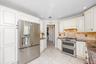 White shaker-style cabinetry, stainless steel French door refrigerator, stainless steel double oven range, mosaic tile backsplash, and light-toned til