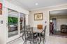 Sliding glass doors opening to a paver patio with a built-in grill station and a pergola