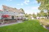 Expansive lawn with a paver patio, stone-faced outdoor kitchen area, and a white pergola structure