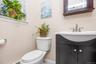 Pedestal sink vanity with dark wood-finish cabinetry, brushed nickel faucet, and a window for natural light