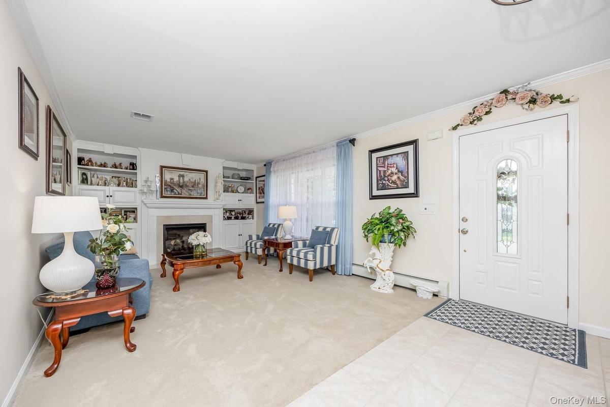 Recessed fireplace with a light-toned surround, built-in shelving, and light-toned wall-to-wall carpeting