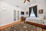 Vaulted ceiling with exposed beams, wood-finish flooring, white French doors, and ceiling fan