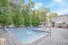Swimming pool with brick coping and integrated steps, surrounded by stone paver patio