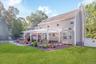 Expansive backyard featuring a manicured lawn, a stone patio with a white pergola, and an outdoor kitchen area with a built-in grill