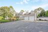 Paved driveway with a two-car garage, dormer windows, covered front porch, and an arched garden gate