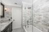 White subway tile shower surround with a rain shower head, glass shower enclosure, white bathtub, and mosaic tile flooring