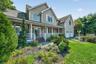 The property is beautifully landscaped with mature trees, lush greenery, and an array of flowering plants.