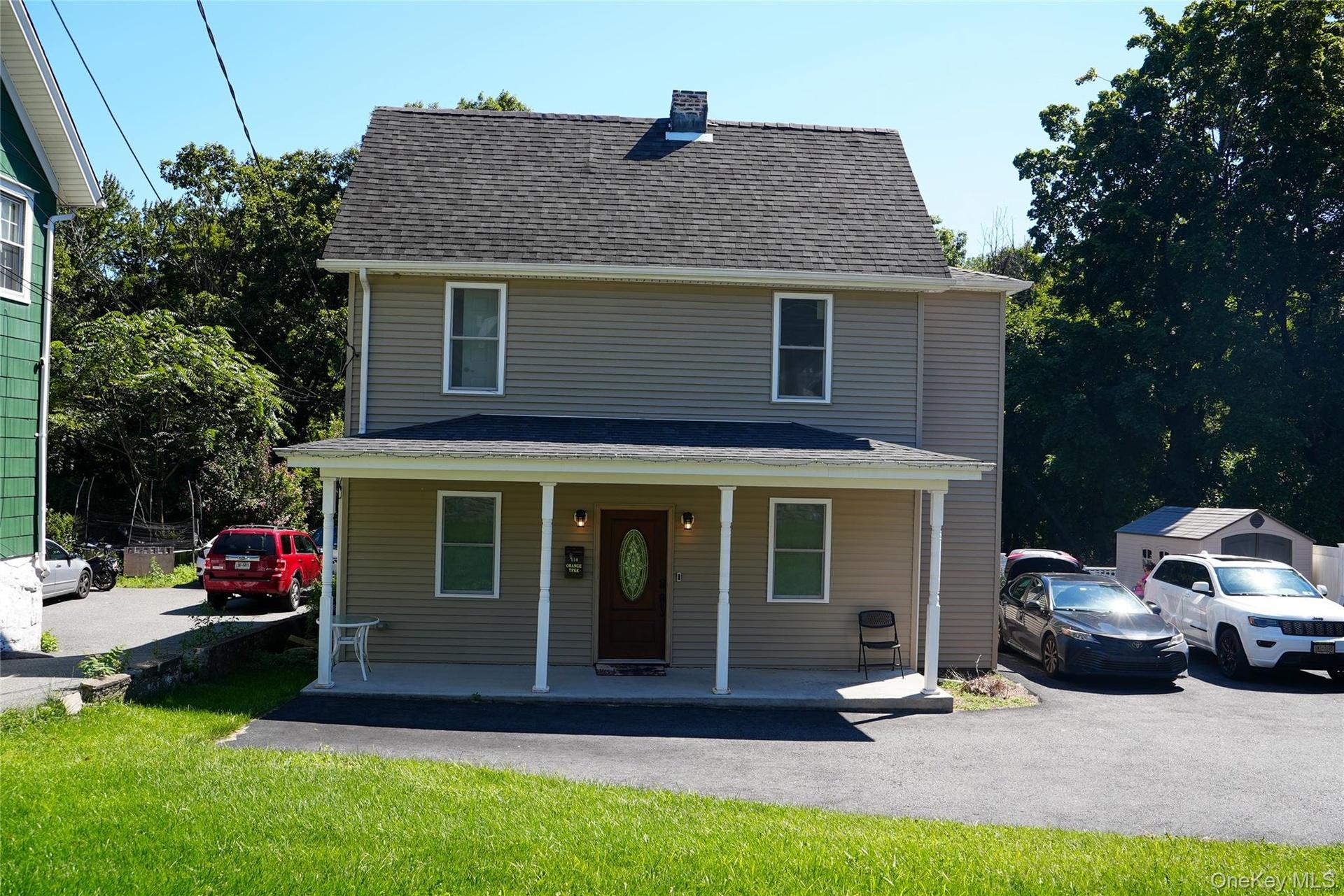Two-story exterior with siding, covered front porch, asphalt driveway, and a shingled roof