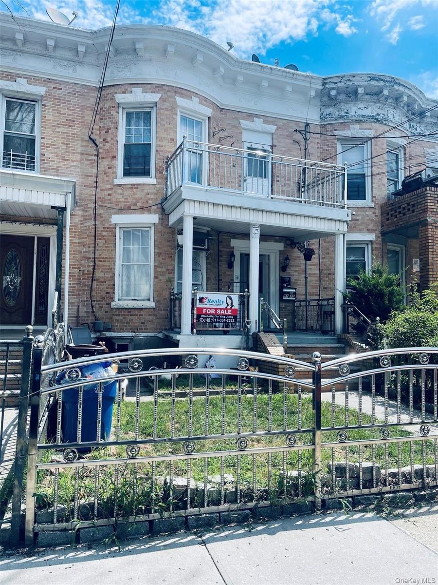 Italianate house with a fenced front yard, brick siding, and covered porch