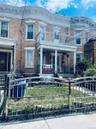 Italianate house with a fenced front yard, brick siding, and covered porch