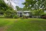Expansive front lawn with mature trees and established landscaping