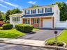 Two-story exterior with brick and siding facade, covered entry, attached garage, paved driveway, and manicured landscaping
