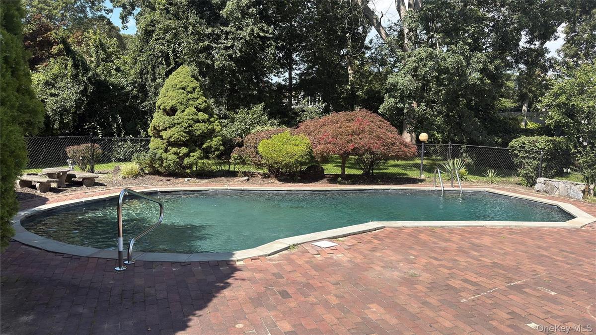 Gunite swimming pool with brick paver surround, stainless steel handrails, and a concrete coping