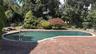 Gunite swimming pool with brick paver surround, stainless steel handrails, and a concrete coping