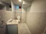 Basement Half Bathroom. Tiled walls and floor, vanity with integrated sink, and a commode