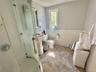 Second Floor Bathroom. Pedestal sink, tile flooring, glass-enclosed shower, white wainscoting, and a window for natural light