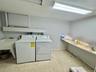 Utility room with a built-in utility sink, overhead fluorescent lighting, and a long built-in shelf