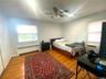 Hardwood flooring, two windows, ceiling fan, and baseboard  Gas heating unit.
