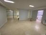 Expansive open-concept room with light-toned flooring, recessed lighting, and a dedicated laundry area featuring a stackable washer and dryer