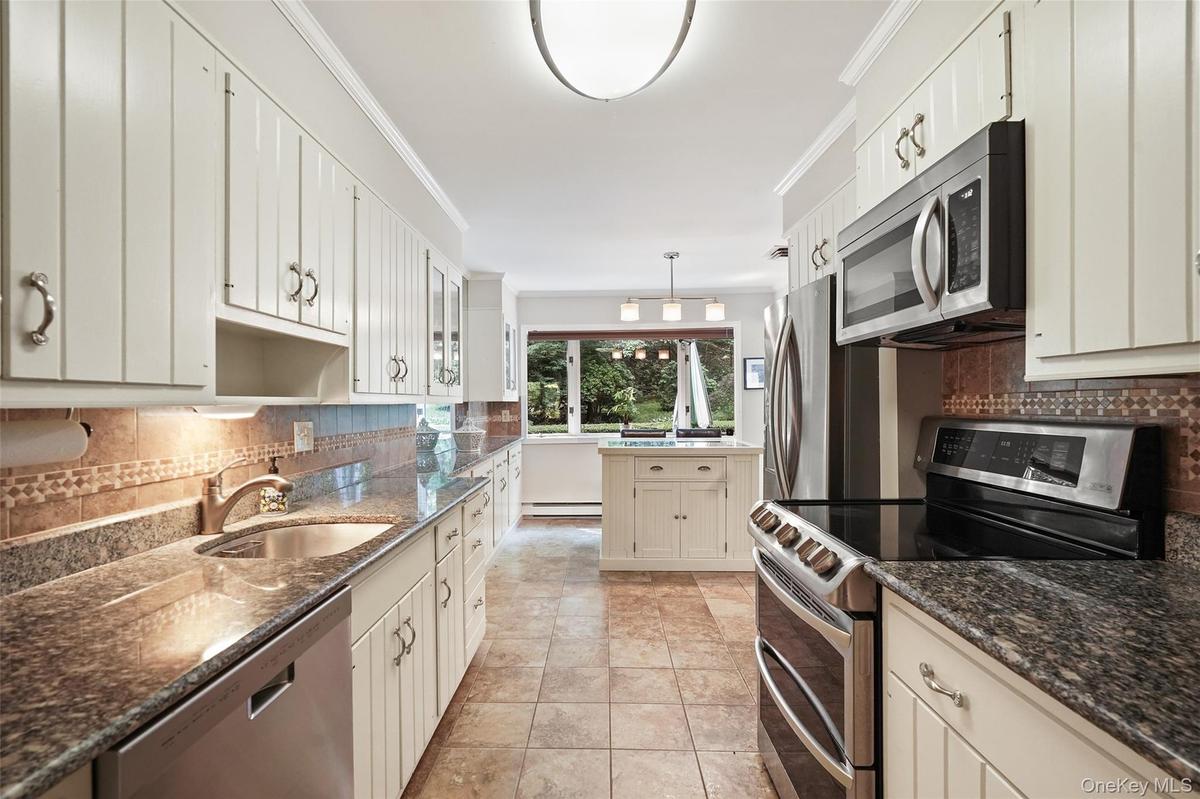 Updated kitchen with granite counters, stainless steel appliances and island with storage
