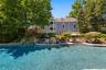 Rear view of house, deck, pool, patio and outdoor kitchen on a summer day.
