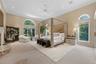 Breathtaking Primary Bedroom with arched entry, 3 large walk-in closets with track lighting with laundry chute, recessed lights, ceiling fan, B/I cabi