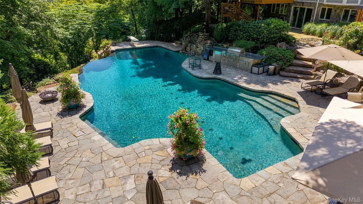 Luxurious free-form pool with no chemicals and surrounded by gorgeous patio with built-in outdoor kitchen, firepit and hot tub.