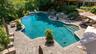 Luxurious free-form pool with no chemicals and surrounded by gorgeous patio with built-in outdoor kitchen, firepit and hot tub.