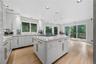 Eat-In-Kitchen with recessed lights, hardwood flooring, glass cabinets, quartzite counters, track lighting, sliding glass door to deck, B/I step stool