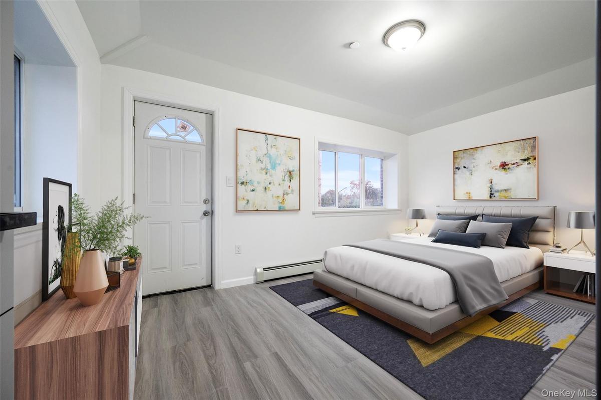 Bedroom featuring a baseboard heating unit and wood finished floors