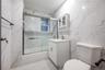 Bathroom with tile walls, bath / shower combo with glass door, and vanity