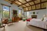 Carpeted bedroom with beamed ceiling and a warm lit fireplace