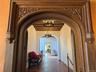 Hall with a chandelier, beam ceiling, a textured wall, and arched walkways