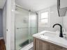 Primary Bathroom: Updated bathroom featuring a wood-finish vanity, white countertop, undermount sink, and sleek matte black faucet.