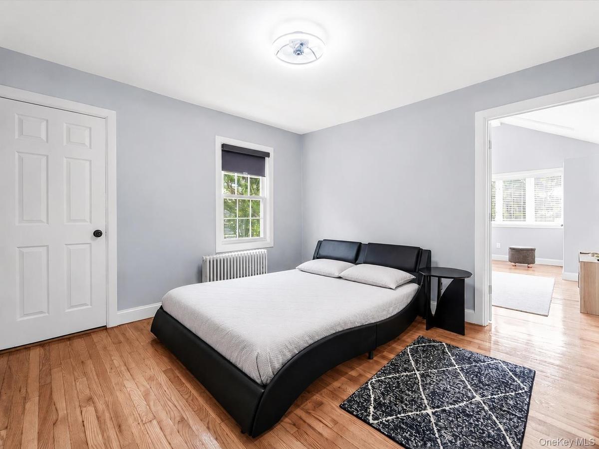 Comfortable bedroom featuring hardwood floors, ample natural light, and radiator heating.