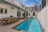 Virtually staged approximately 70-foot pool deck featuring covered outdoor dining, a lounge area, tanning space, and direct access to the main-level p