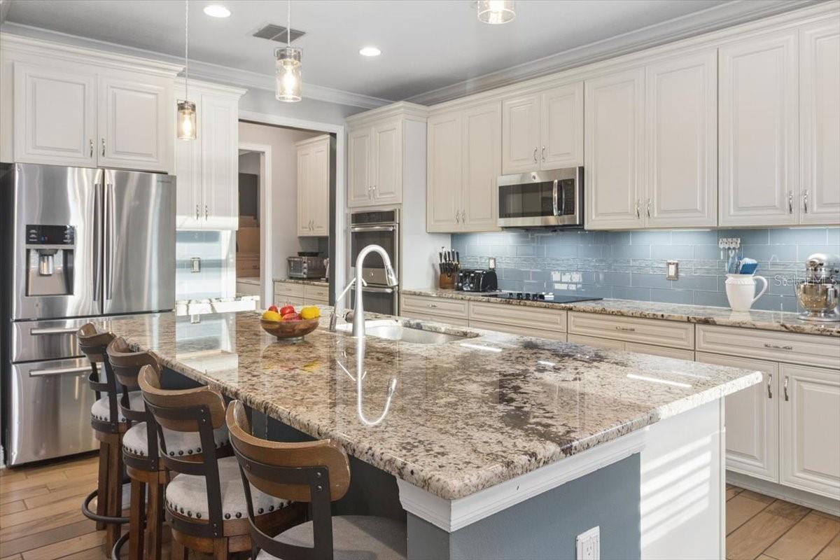 The kitchen features a spacious island with comfortable seating, creating the perfect spot for casual meals, morning coffee, or gathering with family 