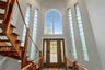 Two-story foyer with an arched transom window, two-panel wood entry door, and vertical glass block windows