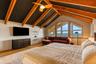 Vaulted ceiling with exposed wood beams, ceiling fan, hardwood flooring, built-in shelving, and large picture windows
