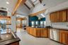 Vaulted ceilings with exposed wood beams, skylights, wood-finish cabinetry, stainless steel appliances, and a subway tile backsplash