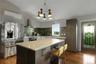 Kitchen featuring a vaulted ceiling, wood-finish flooring, stainless steel appliances, a center island with countertop, and a decorative glass door