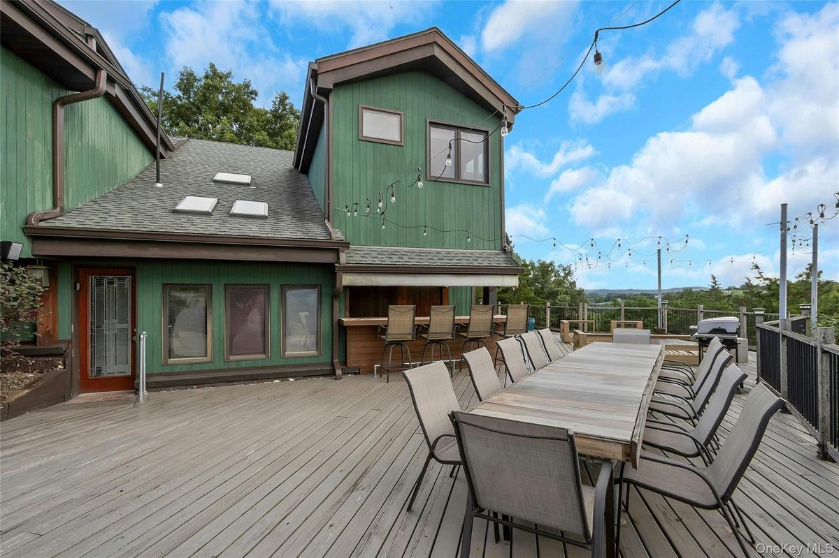 Expansive outdoor deck featuring a built-in bar, extensive railing, and string lighting