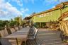 Expansive outdoor decking, multi-level structure, horizontal wood siding, upper-level balcony, and mature trees