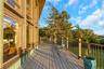 Expansive outdoor deck with wood plank flooring and metal railings, complemented by large vertical windows with wood frames