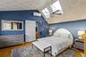Hardwood flooring, sloped ceiling with patterned accent, skylights, ceiling fan, and barn door entry