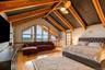 Vaulted ceiling with exposed wood beams, hardwood flooring, large transom windows, and a ceiling fan with light fixture