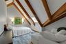 Vaulted ceiling with exposed wood beams, wood-frame window, two wall-mounted sconces, and a skylight