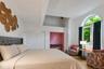 Arched window, wood-finish flooring, white paneled bifold closet doors, built-in recessed area, and a tray ceiling with an angled skylight