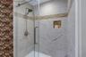 Glass-enclosed shower featuring large format tile with mosaic accent, built-in recessed shelf, and a brushed nickel shower fixture